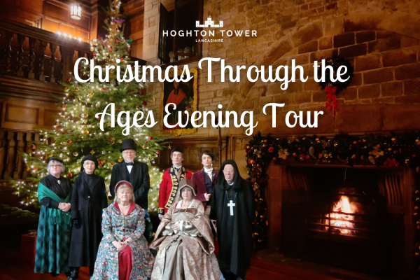 Costumed characters from times gone by standing by the fire in the decorated banqueting hall beside a glowing Christmas tree.