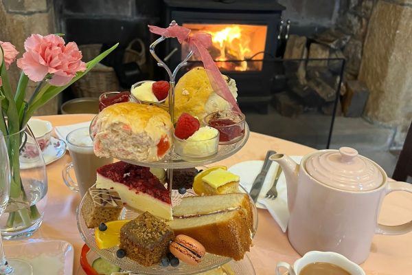 Traditional afternoon tea served at Hoghton Tower Tearoom with scones, cakes, sandwiches, and tea by the fire.
